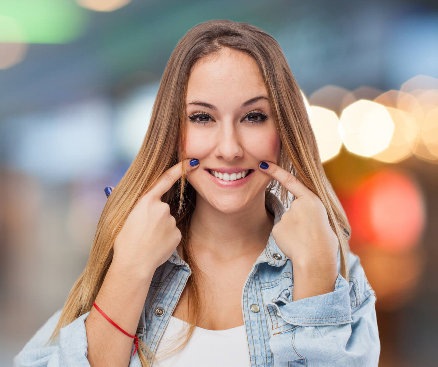 Mulher jovem apontando para o sorriso com dentes claros na Dahdal Aoun Odontologia em Moema, após tratamento para dente escurecido por canal.