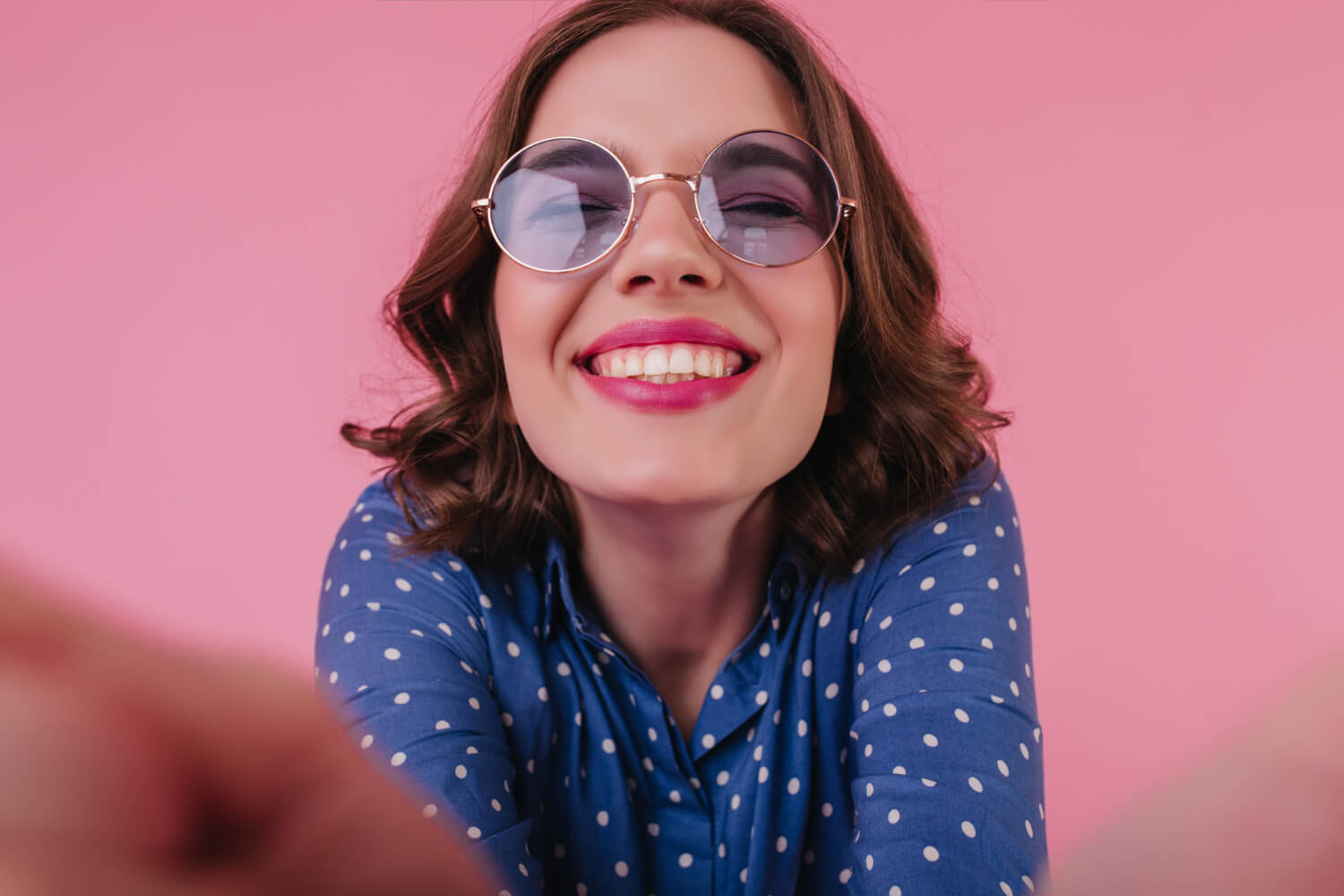 Mulher sorridente de óculos escuros exibe dentes alinhados no tratamento com Invisalign da Dahdal Aoun Odontologia em Indianópolis.