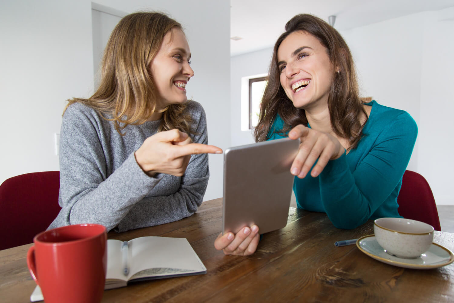 Duas mulheres sorridentes olham tablet ao consultar contenção após o tratamento Invisalign em Indianópolis na Clínica Dahdal Aoun.